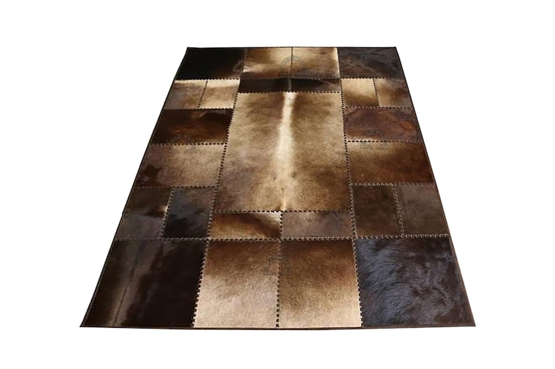 A patchwork cowhide rug with brown and tan squares. The rug is made of real cowhide and has a natural, rustic look.