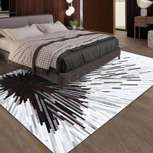 Pu&ograve; includere: Un tappeto in pelle di mucca bianco e nero con un motivo geometrico. Il tappeto &egrave; posizionato in una camera da letto con un letto e un comodino.