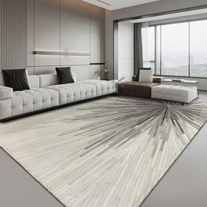 Pu&ograve; includere: Un soggiorno moderno con un divano bianco e un grande tappeto bianco e grigio con un design geometrico. Il tappeto &egrave; realizzato in pelle di mucca e presenta un motivo astratto unico.