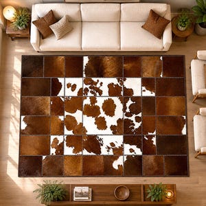 Peut inclure: Un tapis rectangulaire composé d'un assemblage de carrés en peau de vache. Le tapis présente un motif central de taches blanches et brunes entouré d'une bordure de panneaux en peau de vache texturés brun foncé et brun moyen.