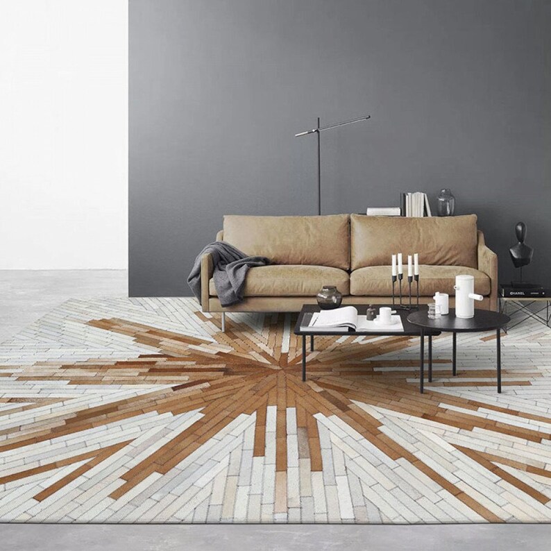 Pu&ograve; includere: Un tappeto geometrico con motivo marrone e bianco con un design a forma di stella. Il tappeto &egrave; in pelle e si trova in un soggiorno con un divano in pelle marrone e un tavolino da caff&egrave; nero.