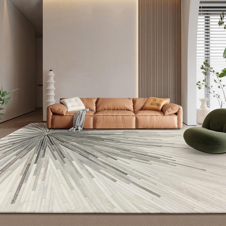 Pu&ograve; includere: Un soggiorno moderno con un divano in pelle marrone e un tappeto geometrico grigio e bianco. Il tappeto ha un motivo a stella con uno sfondo bianco e linee grigie che si irradiano verso l'esterno.