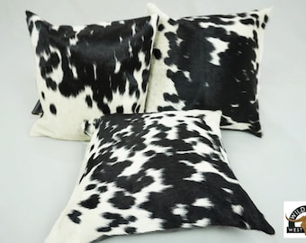 May include: Three black and white cowhide throw pillows. The pillows are made of real cowhide and have a natural, rustic look.