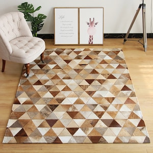 May include: A geometric patterned rug made of cowhide in shades of brown, tan, and white. The rug is made up of a repeating pattern of triangles.