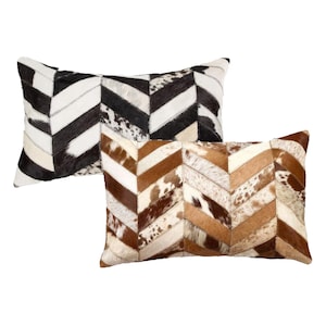 May include: Two decorative pillows with a chevron pattern made from cowhide. The pillows are in black and white and brown and white.