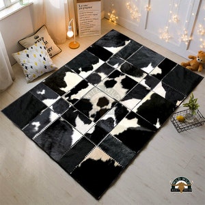 May include: Black and white cowhide patchwork rug with a square design. The rug is made of real cowhide and has a natural, rustic look. It is perfect for adding a touch of Western style to any room.
