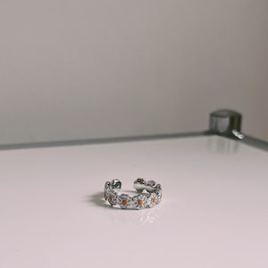 Peut inclure: Une bague en argent avec un motif de marguerite. Les marguerites ont des centres orange.