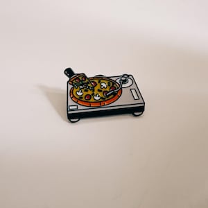 Könnte beinhalten: Eine weiße Keramik-Tasse mit schwarzem Henkel und dem Text "But First, Coffee" in fetter, schwarzer Schrift. Die Tasse steht vor einem verschwommenen Hintergrund, der eine gemütliche Umgebung andeutet.