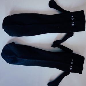 Könnte beinhalten: Ein Paar schwarze Kniestrümpfe mit weißen gestickten Sternen auf der Oberseite jeder Strumpf.
