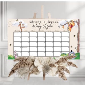 May include: A baby shower calendar with Winnie the Pooh characters. The calendar has a beige background with a grid for dates and the text "Adivina la llegada de baby Azalea". Decorative elements include bees, clouds, and floral accents.