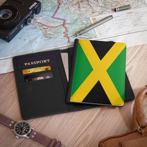 Op de afbeelding: Een zwarte paspoorthouder met het woord "PASSPORT" erop gedrukt. De houder heeft een gleuf voor een creditcard en een vak voor contant geld. De houder is open en een paspoorthoes met de Jamaicaanse vlag is zichtbaar.