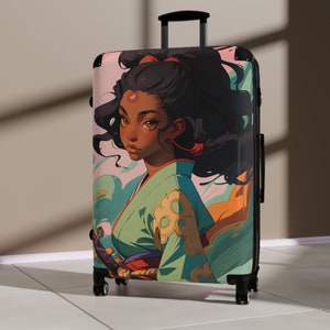 May include: A pink and blue suitcase with a colorful illustration of a woman with long black hair wearing a green and gold kimono. The woman has a red dot on her forehead and is looking to the left.