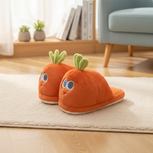 Könnte beinhalten: Ein Paar orangefarbene, karottenförmige Hausschuhe mit grünen Blattoberteilen und Cartoon-Augen. Die Hausschuhe sind aus weichem Material gefertigt und sehen wie Karotten aus. Sie liegen auf einem weißen Teppich.
