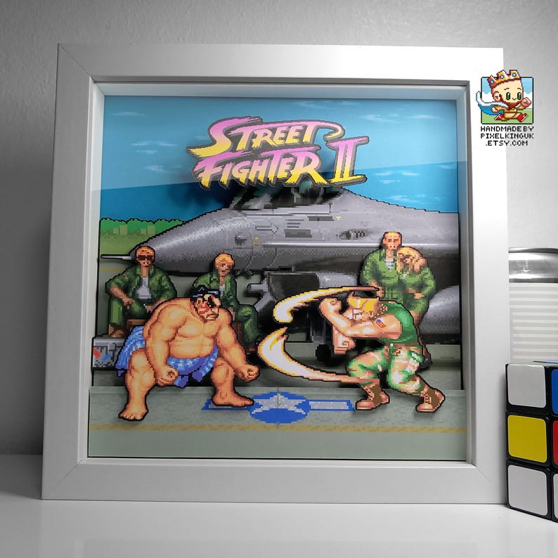 Front view of the framed Street Fighter II E. Honda versus Guile shadow box on the airbase stage.