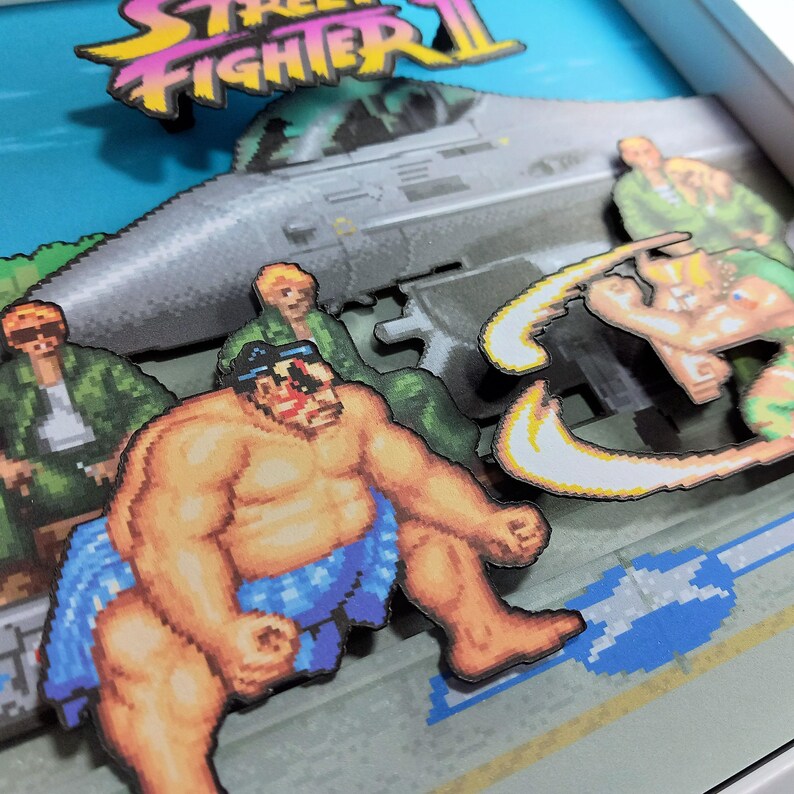 Close-up of the layered artwork showing E. Honda and Guile in front of a military jet.