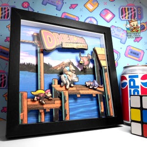 May include: A 3D shadow box art piece featuring a pixelated scene from the video game Dixie Kong's Double Trouble. The display shows characters on a wooden dock over blue water with a mountain background, all encased in a black frame.