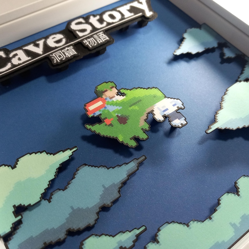 May include: A 3D papercraft diorama of the video game Cave Story, featuring a green pixelated character on a floating island against a blue background with white clouds.