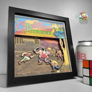 Puede incluir: Un diorama 3D enmarcado del videojuego 'Cadillac and Dinosaurs' de Capcom. El diorama presenta personajes del juego, incluido un dinosaurio, en un entorno de jungla.