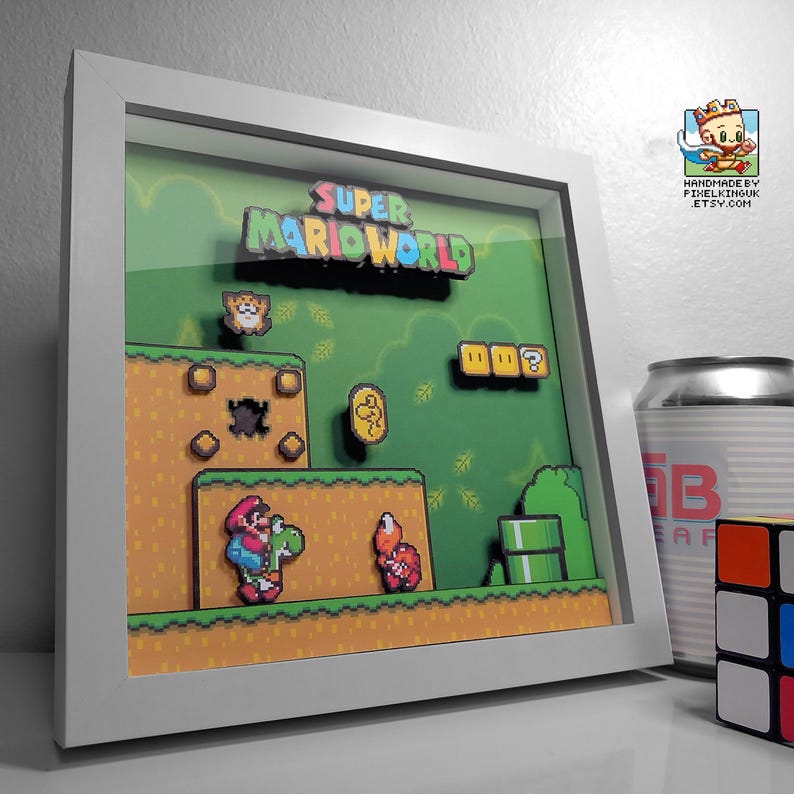 Angled view of the Super Mario World Yoshi’s Island shadow box in a white frame, showing Yoshi facing a red enemy in a green platform scene.