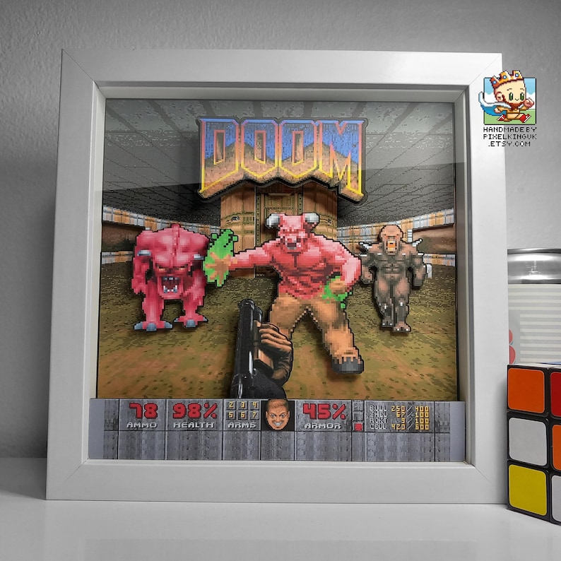 Front view of a white-framed classic DOOM shadow box showing demons approaching the player above the game HUD.