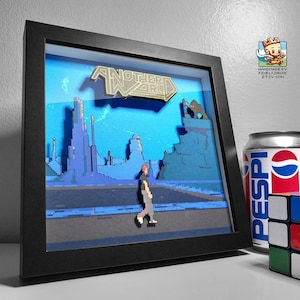 Puede incluir: Una escena de arte pixelado 3D enmarcada del videojuego "Another World". La obra presenta una figura caminando por un camino, con un paisaje azul y gris de fondo. El marco es negro, y se ven una lata de Pepsi y un cubo de Rubik.