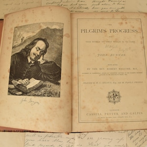 May include: An antique book titled "Pilgrim's Progress" by John Bunyan. The book is open to a page with an illustration of a man reading a book. The book is bound in brown leather and has a worn, aged appearance.