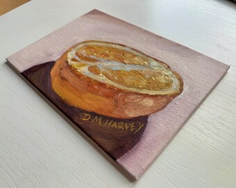 Puede incluir: Un primer plano de una pintura de una naranja cortada por la mitad con una piel marrón claro y un interior amarillo. La pintura está firmada "DM Harvey" en la esquina inferior derecha.