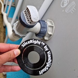 Könnte beinhalten: Ein schwarzes Kunststoff-Poolzubehör mit dem weißen Text "SliceRight™ by VanDijkStuff". Das Zubehör wird in der Nähe der Wasserzulauf- und -auslaufrohre eines Pools gehalten. Die Rohre sind weiß und grau, und die Poolwand ist grau.