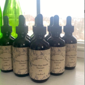 May include: Seven brown glass bottles with dropper tops and labels that read "Wildflower Farm White Pine Needle Tincture 2oz".