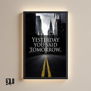 May include: Black framed print featuring a cityscape with a road and yellow lines leading to the horizon. The text "YESTERDAY YOU SAID TOMORROW" is displayed in white. The print has a black border and a neutral background.