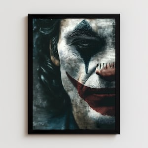 Puede incluir: Una impresión artística enmarcada que presenta un primer plano de un rostro con maquillaje blanco, una sonrisa roja y un triángulo azul en la frente. El fondo es un collage de recortes de periódicos. El marco es negro.