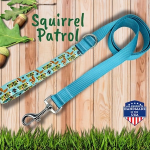 May include: A turquoise dog leash with a matching collar featuring a squirrel and paw print pattern. The leash has a silver metal clasp and a "Squirrel Patrol" design. The product is handmade in the USA.