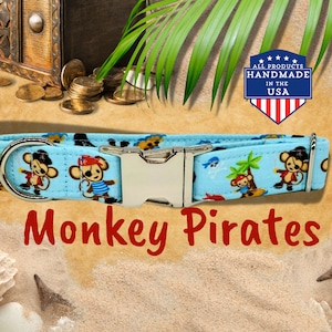 May include: A blue dog collar featuring a monkey pirate design. The collar has a silver buckle and a silver D-ring. The collar is set against a sandy background with a wooden treasure chest and coins visible. The text "Monkey Pirates" is written in red below the collar. The text "ALL PRODUCTS HANDMADE IN THE USA" is in a red circle with white stars and a red, white, and blue American flag.