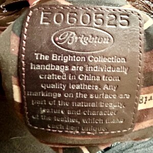 May include: A brown leather tag with the text "E060525 Brighton" and the text "The Brighton Collection handbags are individually crafted in China from quality leathers. Any markings on the surface are part of the natural beauty, texture and character of the leather, which makes each bag unique."