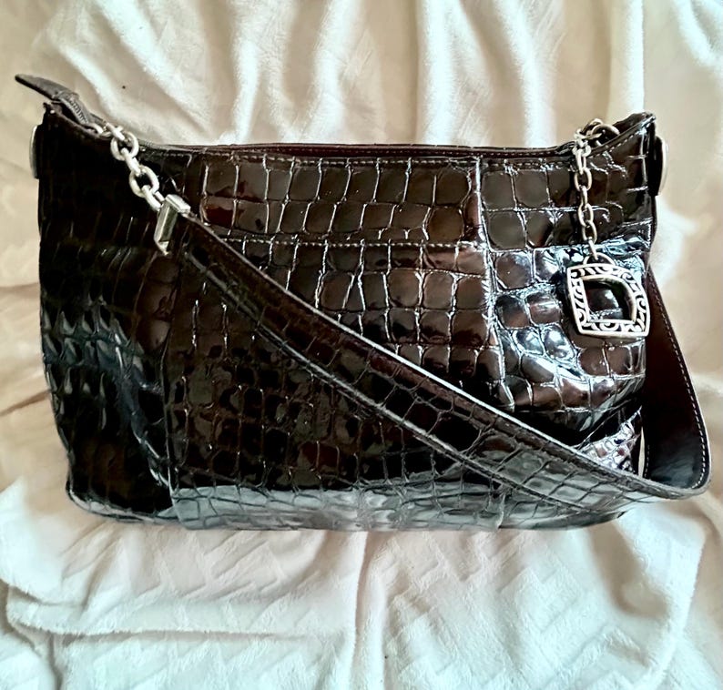 May include: A brown crocodile embossed leather handbag with a silver chain strap and a silver clasp.