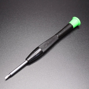 Può includere: Un piccolo cacciavite nero con punta verde. L'impugnatura è strutturata per una presa salda e l'asta metallica è argentata. Questo utensile di precisione è progettato per elettronica o piccoli lavori meccanici.