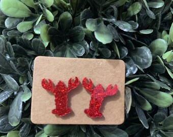 May include: A pair of red glitter lobster earrings on a brown card.