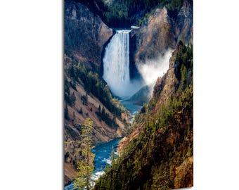 May include: A vertical wall art print featuring a high-angle view of a powerful waterfall cascading into a deep canyon. The scene includes rugged, rocky cliffs with patches of green pine trees and a winding blue river flowing through the valley floor.