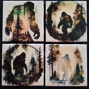 May include: Set of four square ceramic tiles featuring Bigfoot illustrations. Each tile showcases a different watercolor design of Bigfoot in a forest setting, with varying color palettes of greens, browns, and blues. The tiles are arranged in a 2x2 grid.