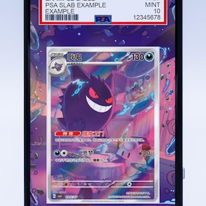 May include: A graded Pokémon trading card featuring a purple Gengar character with a large grin. The card is encased in a protective slab with a white label displaying details and a barcode. The label reads "EXAMPLE LABLE" and "PSA SLAB EXAMPLE".