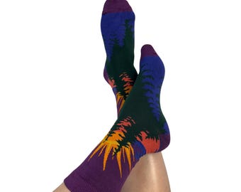 May include: A pair of colorful socks with a forest design. The socks feature a purple cuff and toe, with a blue and green forest scene and an orange and yellow sunset design. The socks are made of a soft, comfortable material.