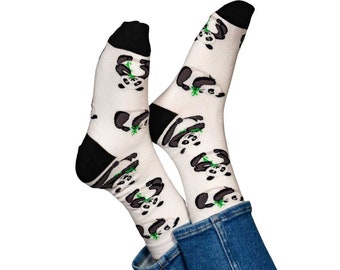 May include: A pair of white socks with a repeating pattern of black and white panda bears eating green bamboo. The socks have black heels and toes. The socks are worn with blue jeans.
