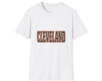 May include: A white short-sleeved t-shirt featuring the word CLEVELAND printed in a bold, block-style font across the chest. The lettering is dark brown with a thin red outline, creating a clear and legible graphic on the plain white fabric.