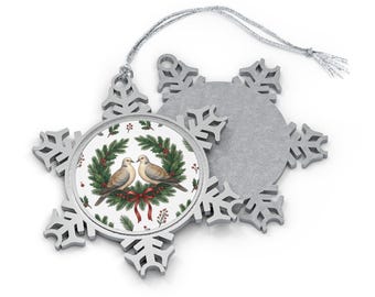 May include: A silver-toned metal snowflake ornament featuring a circular insert with two doves perched within a green pine wreath adorned with red berries and a red bow. The ornament includes a silver hanging string for display purposes.