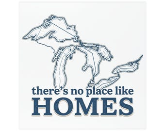 May include: A square graphic print featuring a dark blue outline map of the Great Lakes. Below the map, the text reads there's no place like HOMES in dark blue, bold, sans-serif lettering against a plain white background.