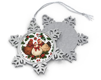 May include: A silver snowflake-shaped ornament featuring a circular insert with a printed illustration of three chickens wearing red bows, surrounded by green holly leaves and red berries, attached to a thin silver hanging string.