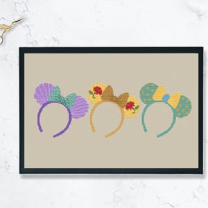 Könnte beinhalten: Drei Paar bunte Disney-Mausohren mit Schleifen. Die Ohren sind lila, gelb und grün mit Blumen- und Muschelmotiven.