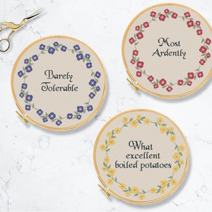 May include: Three embroidery hoops with floral wreaths and text. The first hoop has a blue floral wreath with the text "Barely Tolerable". The second hoop has a red floral wreath with the text "Most Ardently". The third hoop has a yellow floral wreath with the text "What excellent boiled potatoes".