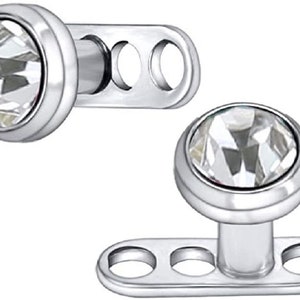 May include: Two surgical steel nipple barbell jewelry pieces with clear crystal gems. Each barbell has a flat base with three holes for secure placement.