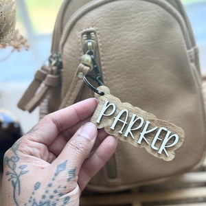 May include: A light brown leather backpack with a wooden name tag that says "Parker" attached to it.